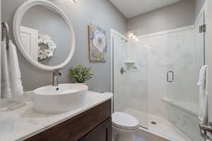 Bathroom featuring vanity, toilet, and a shower with shower door