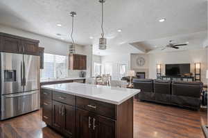 Kitchen featuring stainless steel fridge, a center island, a textured ceiling, and sink