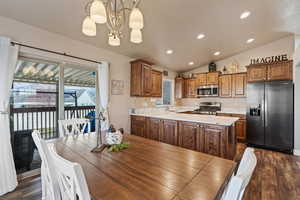 Dining area featuring a notable chandelier, dark hardwood / wood-style flooring, lofted ceiling, and sink