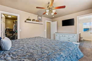 Carpeted bedroom with connected bathroom, a spacious closet, a closet, and ceiling fan