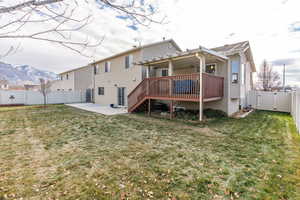 Rear view of property with a lawn, a deck with mountain view, a patio, and cooling unit