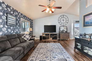 Living room featuring lofted ceiling, ceiling fan, and dark wood-type flooring