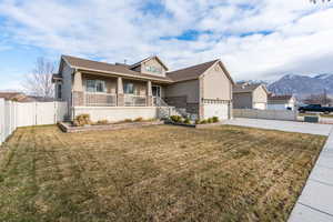 View of front of house with a mountain view, a garage, covered porch, and a front lawn