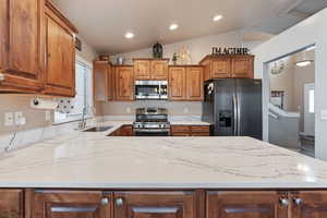 Kitchen featuring sink, lofted ceiling, and appliances with stainless steel finishes