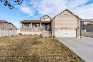 View of front of home featuring covered porch, a front yard, and a garage