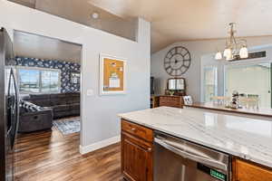 Kitchen featuring decorative light fixtures, dark hardwood / wood-style floors, a notable chandelier, light stone counters, and stainless steel appliances