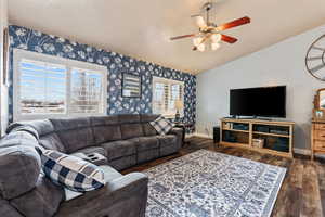 Living room with vaulted ceiling, ceiling fan, and dark wood-type flooring