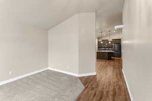 Unfurnished living room featuring dark hardwood / wood-style floors and vaulted ceiling