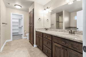 Bathroom with a textured ceiling, vanity, toilet, and tile patterned floors