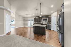 Kitchen with decorative backsplash, dark brown cabinets, stainless steel appliances, pendant lighting, and a center island