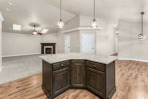 Kitchen featuring pendant lighting, dark brown cabinets, a center island, and ceiling fan