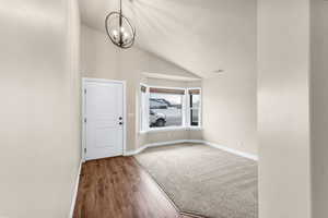 Entrance foyer with hardwood / wood-style flooring, lofted ceiling, and a notable chandelier