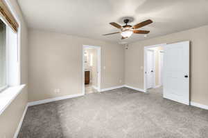 Unfurnished bedroom featuring ceiling fan, light carpet, connected bathroom, and multiple windows