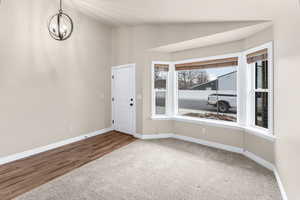 Spare room featuring carpet, vaulted ceiling, and an inviting chandelier