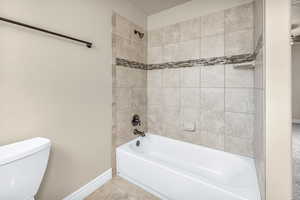 Bathroom with tile patterned flooring, tiled shower / bath combo, and toilet