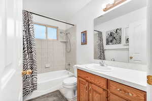 Full bathroom with toilet, tile patterned floors, vanity, and shower / tub combo with curtain