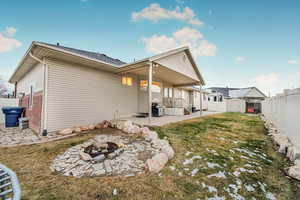 Back of property featuring a shed, a patio area, a yard, and a fire pit