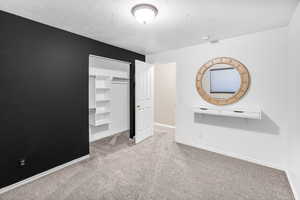 Unfurnished bedroom with light carpet and a textured ceiling