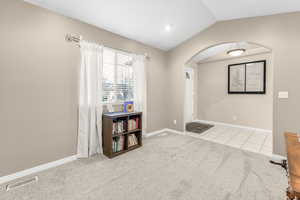 Interior space with light colored carpet and lofted ceiling