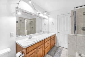 Bathroom with tile patterned flooring, vanity, toilet, and an enclosed shower