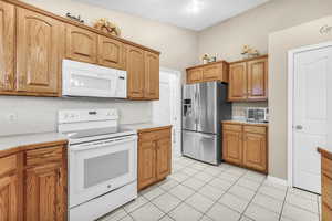 Kitchen featuring tasteful backsplash, light tile patterned flooring, and white appliances