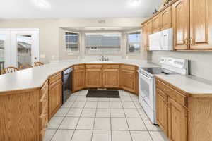 Kitchen featuring white appliances, a kitchen breakfast bar, sink, light tile patterned flooring, and kitchen peninsula