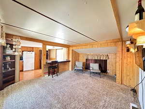 Carpeted living room featuring wooden walls