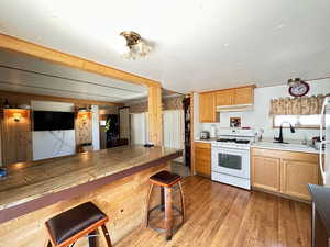 Kitchen featuring white range with gas cooktop, sink, and light hardwood / wood-style flooring