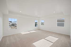 Carpeted spare room featuring a tray ceiling