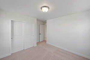 Unfurnished bedroom with light colored carpet and a closet