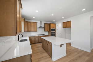 Kitchen featuring a center island, backsplash, wall chimney range hood, sink, and built in microwave