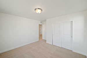 Unfurnished bedroom with light carpet and a closet