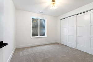 Unfurnished bedroom with light carpet and a closet