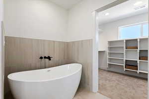 Bathroom featuring tile patterned floors, a bathtub, and tile walls