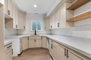 Kitchen featuring decorative backsplash, cream cabinets, sink, and light wood-type flooring