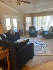 Carpeted living room with ceiling fan, a healthy amount of sunlight, a textured ceiling, and french doors