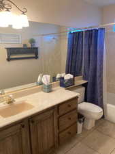 Full bathroom featuring tile patterned floors, shower / tub combo with curtain, vanity, and toilet