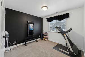 Exercise area featuring light carpet and a textured ceiling