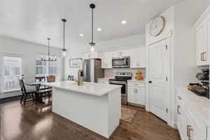 Kitchen with a kitchen island with sink, hanging light fixtures, sink, appliances with stainless steel finishes, and white cabinetry