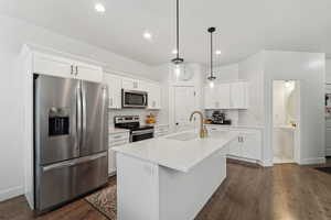 Kitchen featuring pendant lighting, a center island with sink, white cabinets, sink, and appliances with stainless steel finishes