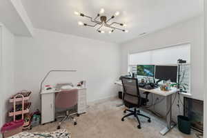 Office area with light carpet, a healthy amount of sunlight, and a notable chandelier