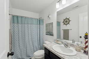 Bathroom with a shower with curtain, vanity, and toilet