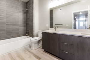 Full bathroom featuring toilet, hardwood / wood-style floors, vanity, and tiled shower / bath