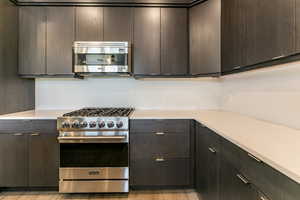 Kitchen with dark brown cabinets, appliances with stainless steel finishes, and light hardwood / wood-style flooring