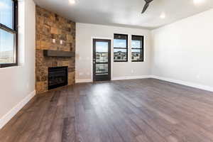 Unfurnished living room featuring a fireplace, dark hardwood / wood-style floors, and ceiling fan