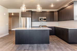 Kitchen featuring dark brown cabinets, stainless steel appliances, and light hardwood / wood-style flooring