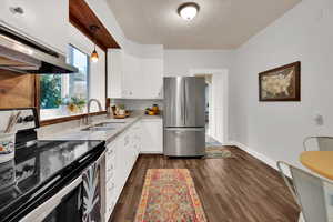 Kitchen with pendant lighting, sink, white cabinetry, stainless steel appliances, and extractor fan