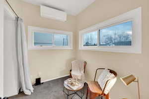 Sitting room featuring an AC wall unit and carpet flooring