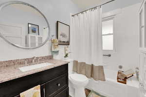 Full bathroom with shower / bathtub combination with curtain, backsplash, toilet, vanity, and tile walls