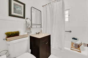 Full bathroom with vanity, shower / bath combination with curtain, tile walls, and toilet